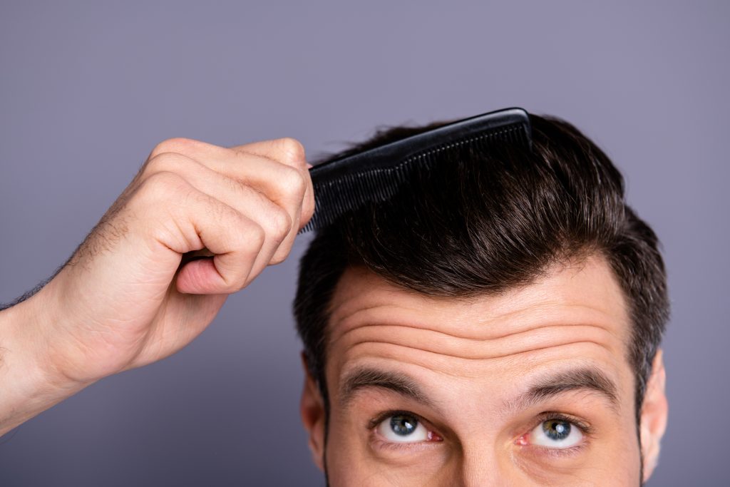 Man combing his thick brown hair to represent Barbershop for Male Haircuts Downers Grove.