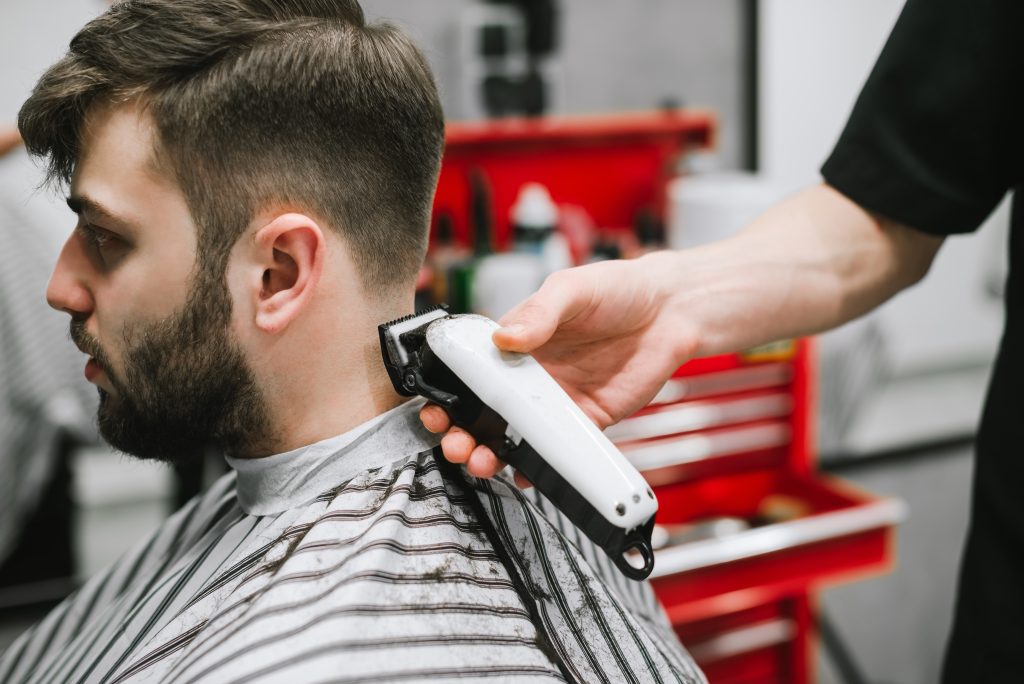 Stylist using hair clipper on man's neckline concept for Men Haircuts Near Willowbrook.